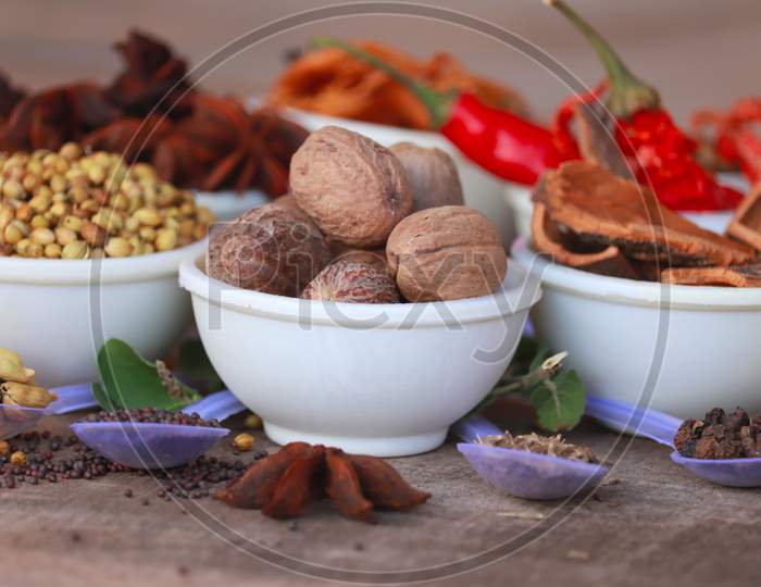 Group Of Indian Spices And Herbs Difference Ware On Wooden Teblet,Different Spices In Spoons On Table,Indian Bay Leaf, Garam Masala, Mace, Javitri, Nutmeg, Jaipha