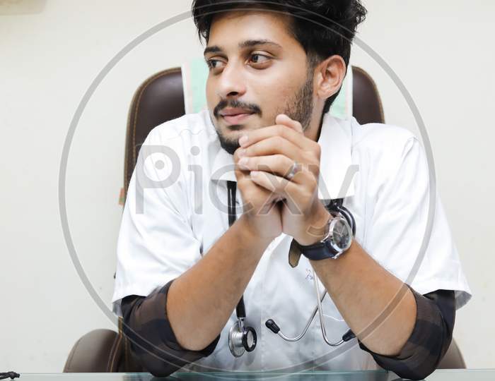 Indian young doctor sitting on chair, doctor office, doctor in clinic