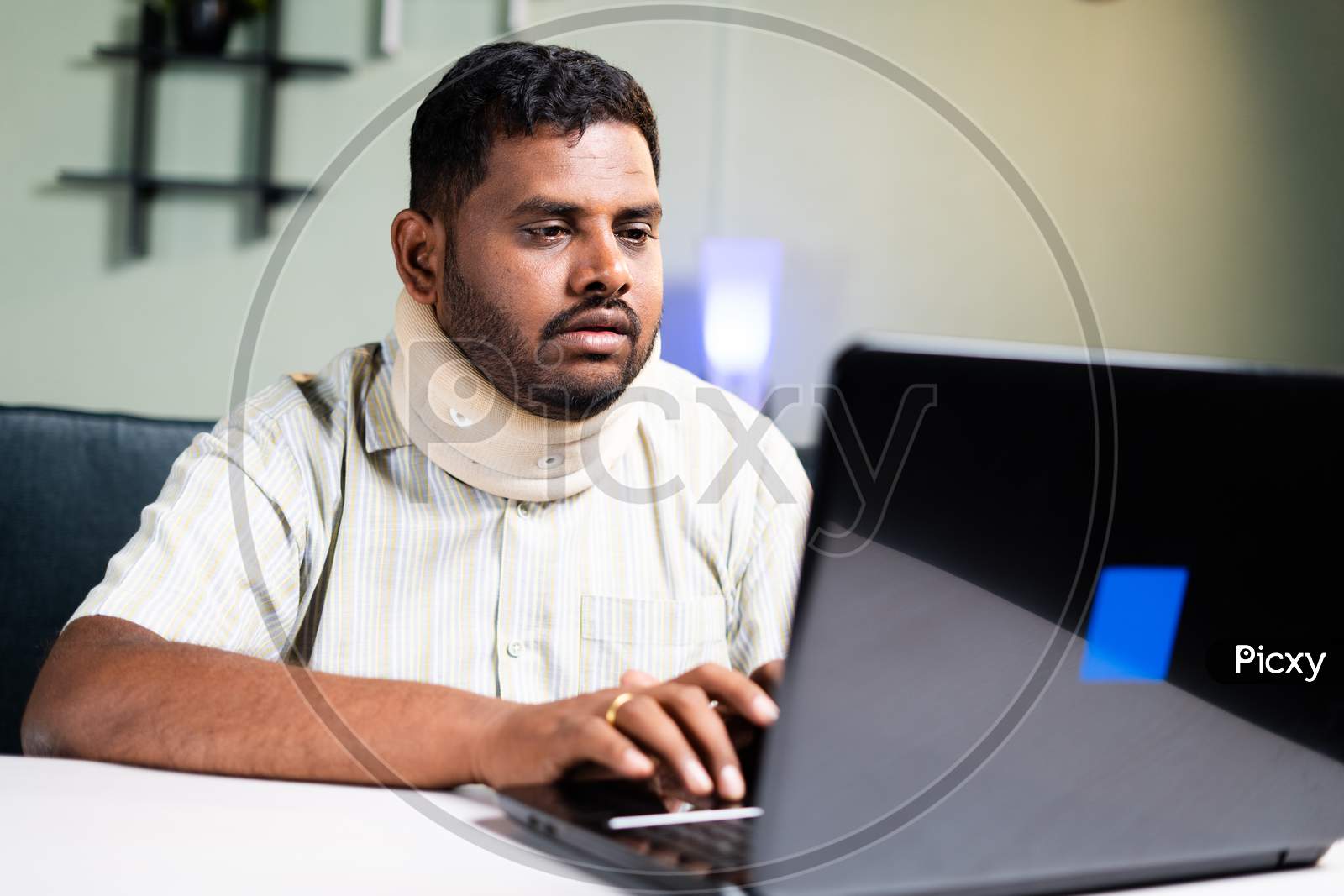 Fat Man With Neck Brace Working On Laptop Due To Neck Pain During Work From Home - Concept Of Overworking And Unhealthy Food Habits During Coronavirus Covid-19 Pandemic.