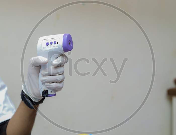 Doctor in a mask protective mask use infrared forehead thermometer to check body temperature for virus symptoms. Thermometer gun. Virus concept. Coronavirus.