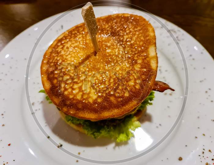 A Tasty Grilled Burger With Tomatoes And Salad On A White Plate