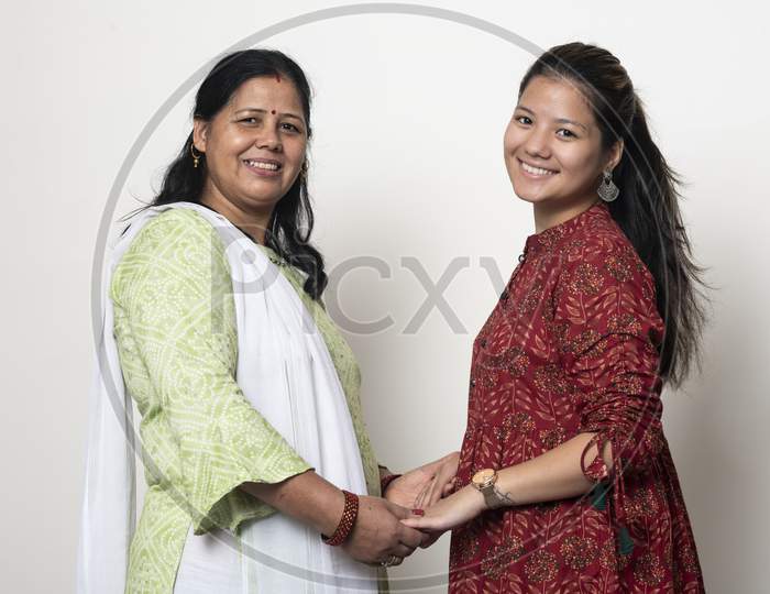 Young Indian Girl Posing With Her Mother And Looking Into The Camera. Mother And Daughter Concept. Daughter Celebrating Mother'S Day. Captured In White Isolated Background.