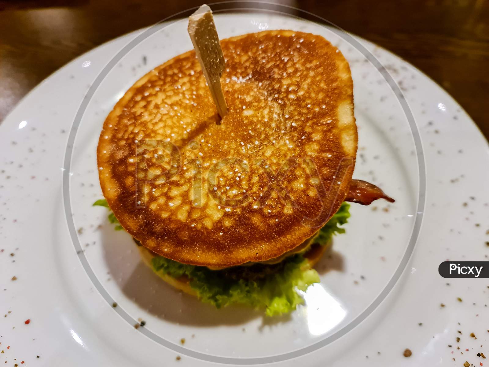 A Tasty Grilled Burger With Tomatoes And Salad On A White Plate