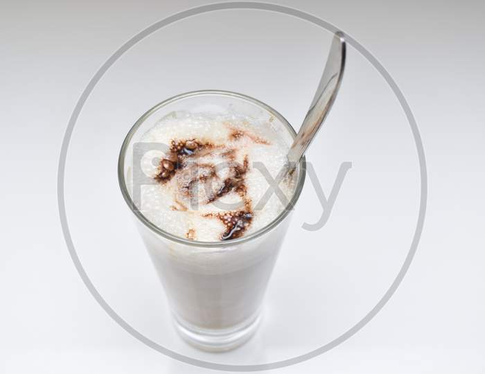 Cold Coffee With Chocolate Syrup In Glass With Spoon On White Background