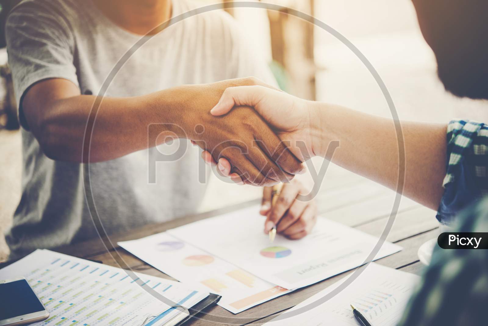 Close-Up Of Two Business People Shaking Hands While Sitting At The Working Place.
