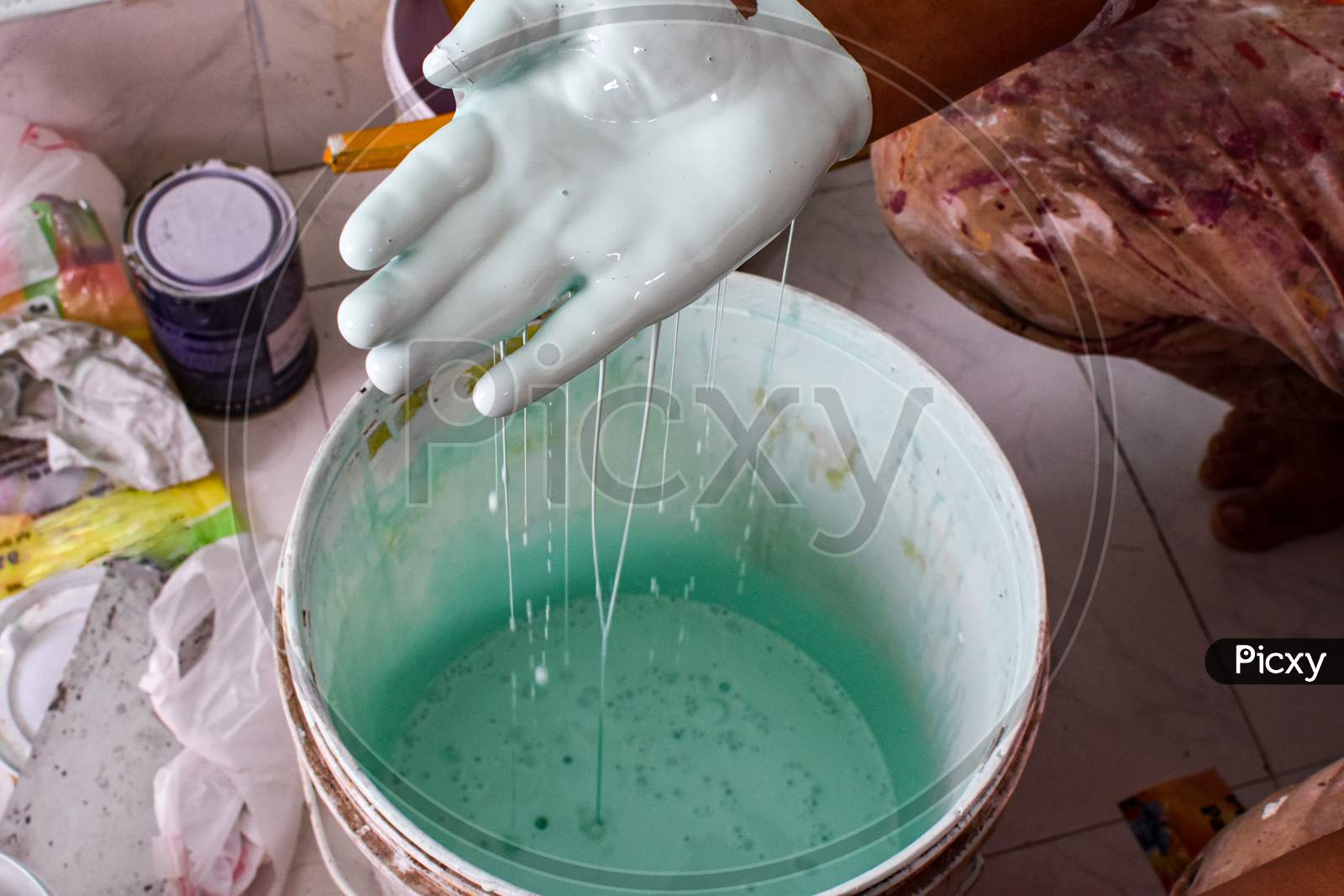 Hand Mixing Green Paint In A Plastic Bucket