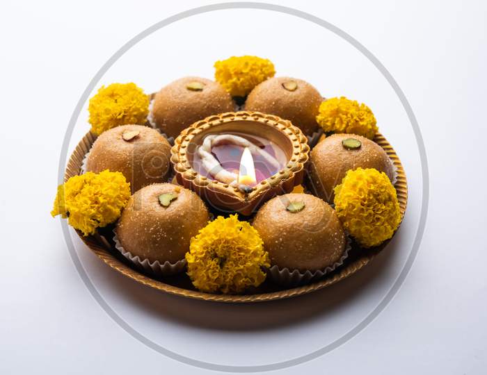 Besan Ladoo And Diwali Diya Or Clay Lamp Decorated In A Plate With Marigold Flowers - Happy Diwali Greeting
