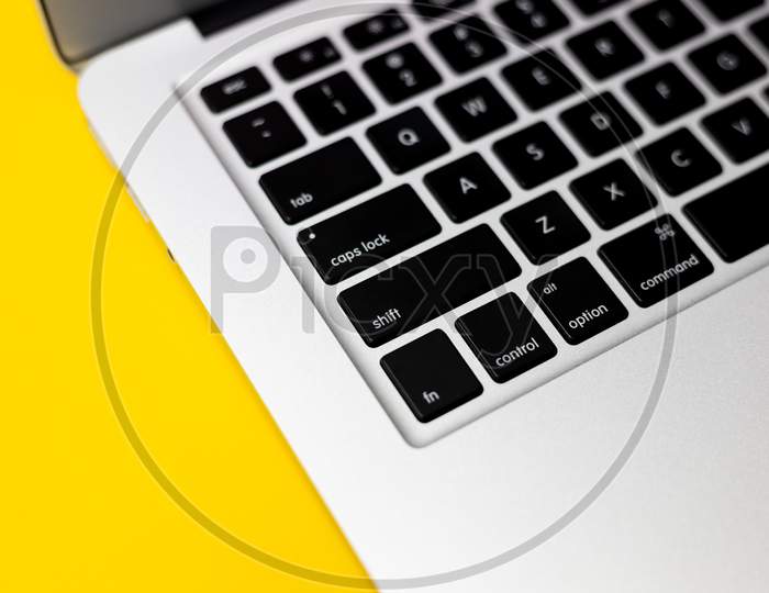 Flat lay, top view, closeup profile shot of Laptop Keyboard on yellow background
