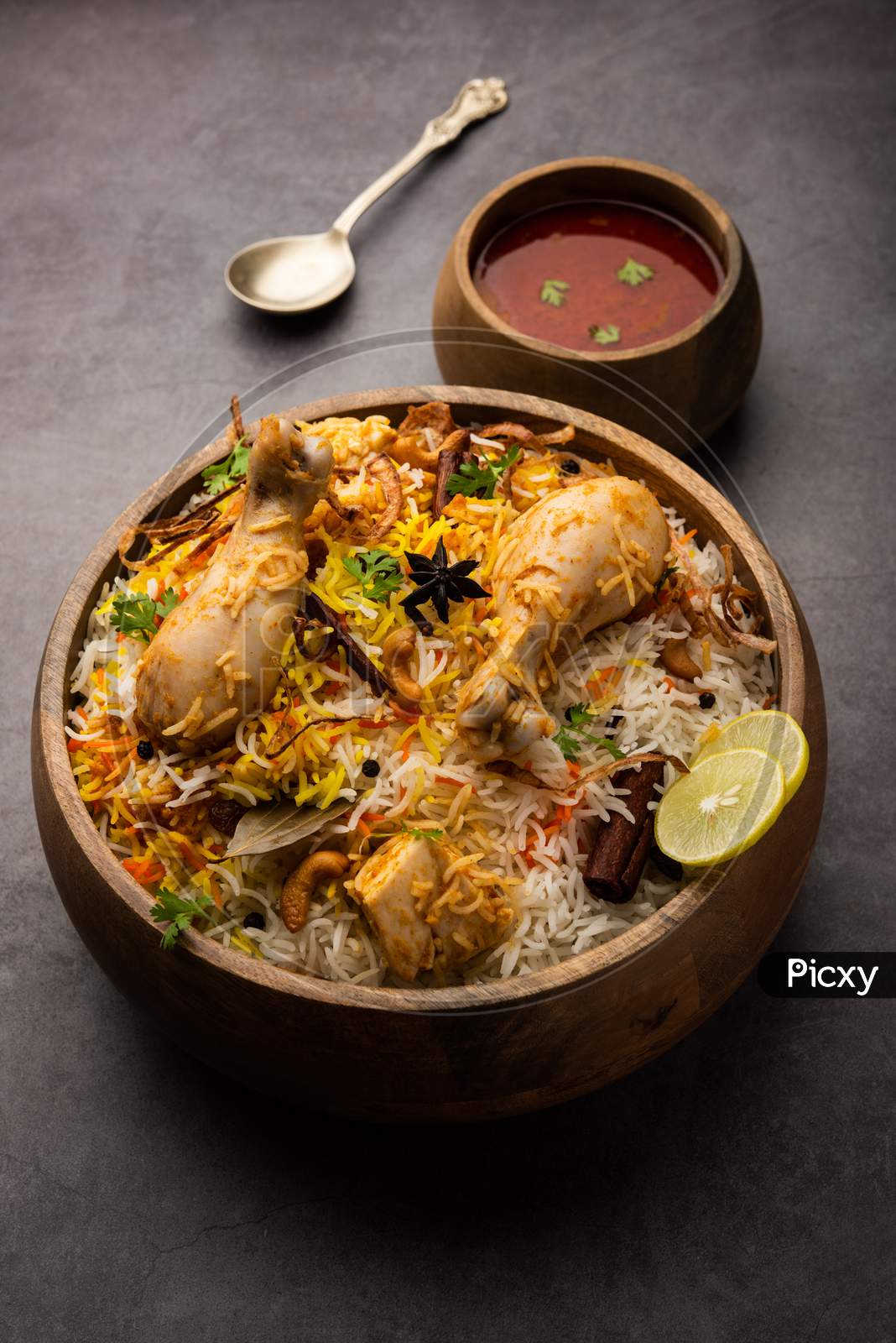 Indian Chicken Biryani Served In A Terracotta Bowl With Yogurt Over White Background. Selective Focus