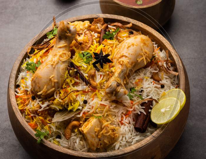 Indian Chicken Biryani Served In A Terracotta Bowl With Yogurt Over White Background. Selective Focus