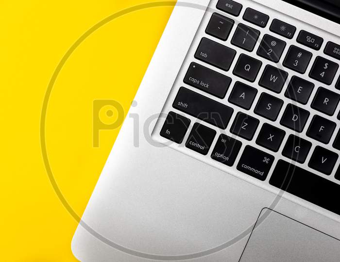 Flat lay, top view of Laptop computer keyboard on a bright yellow background. Closeup macro aesthetic profile shot of keyboard. Work from home WFH workspace - angle 3