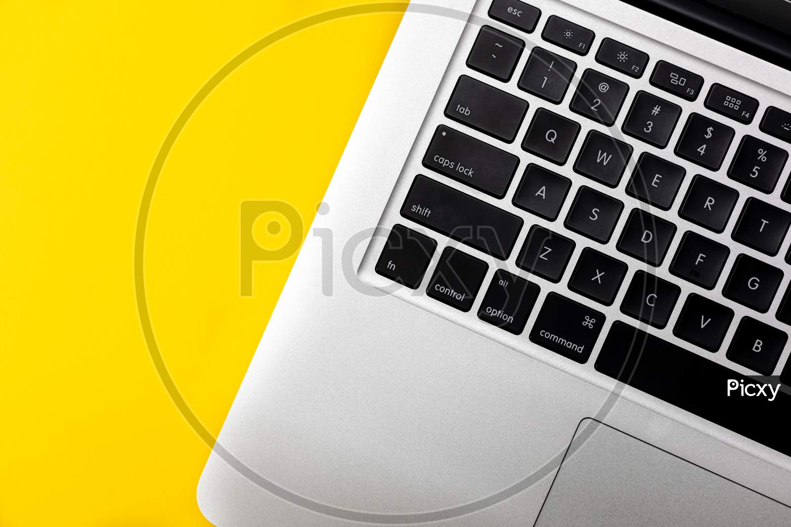Flat lay, top view of Laptop computer keyboard on a bright yellow background. Closeup macro aesthetic profile shot of keyboard. Work from home WFH workspace - angle 3