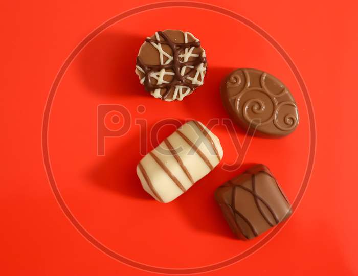 Very Tasty Chocolates From Chocolate And Nougat On A Red Background.