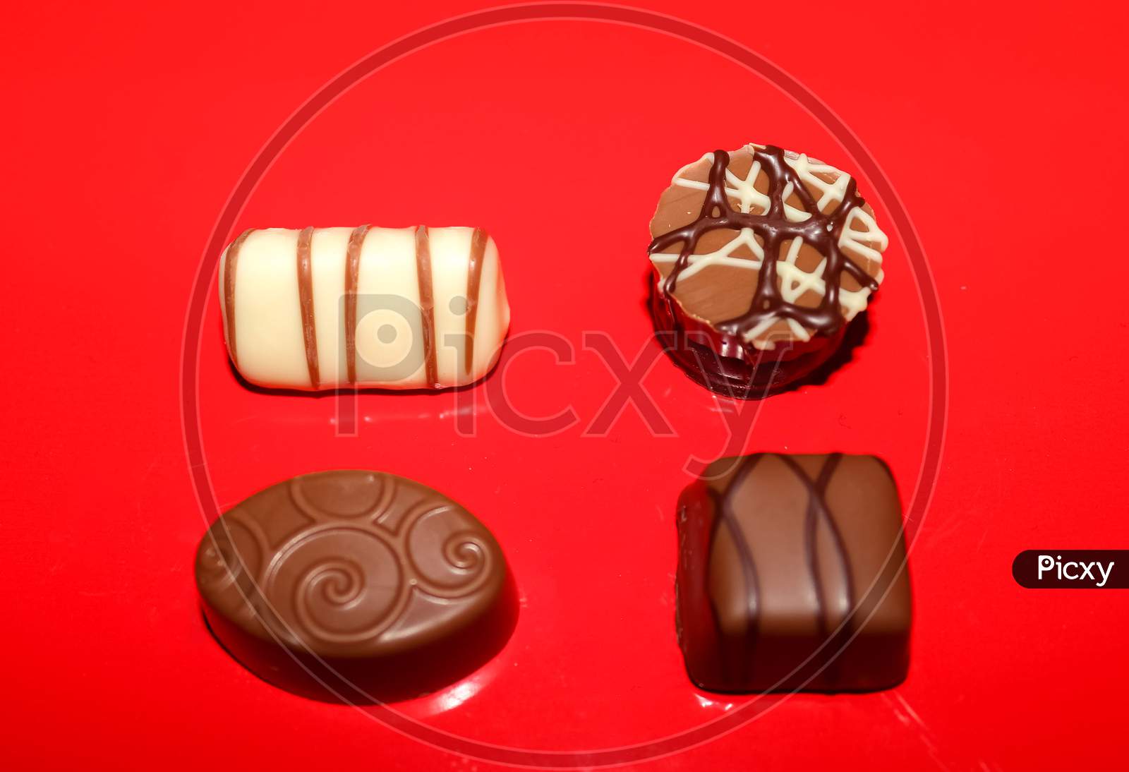Very Tasty Chocolates From Chocolate And Nougat On A Red Background.
