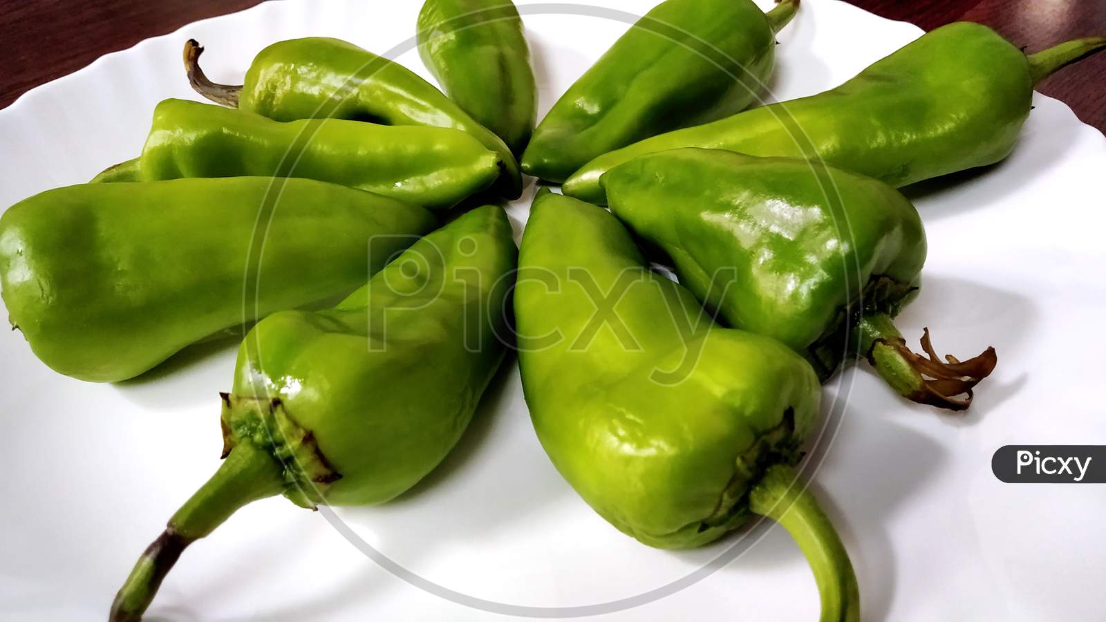 Big And Fresh Green Chilies Arranged On A White Plate