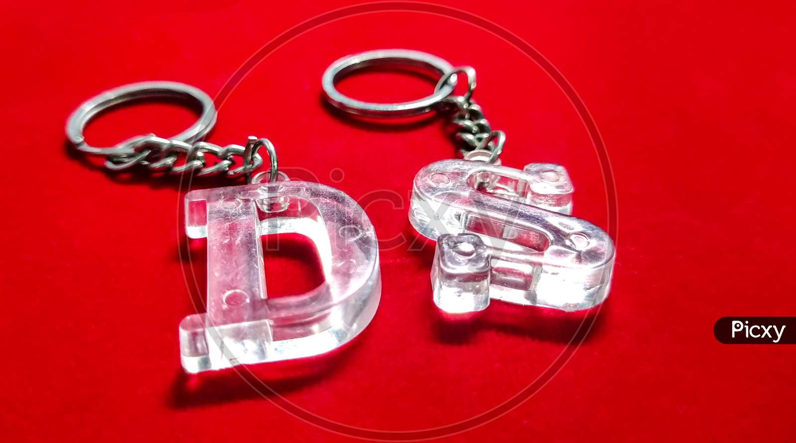 Close-Up Shot Of A Trinket With The Capital Letters "D" And "S" Isolated On A Red Background