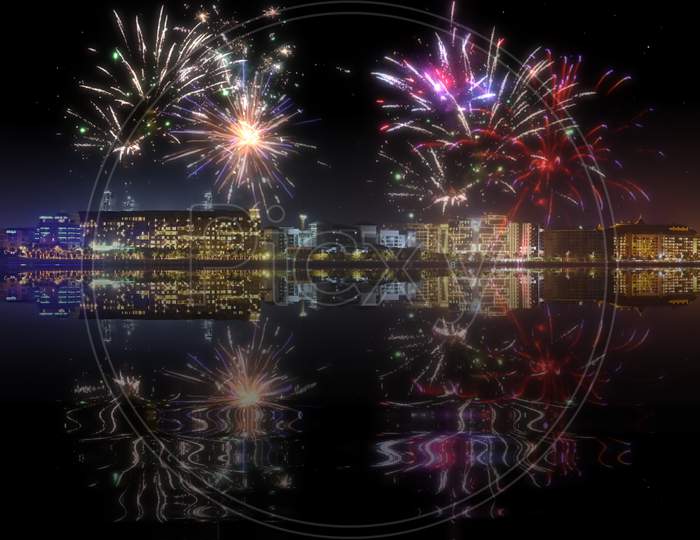 Beautiful Happy New Year Fireworks Above A City Skyline With Reflections On Water