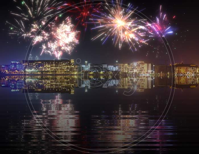 Beautiful Happy New Year Fireworks Above A City Skyline With Reflections On Water