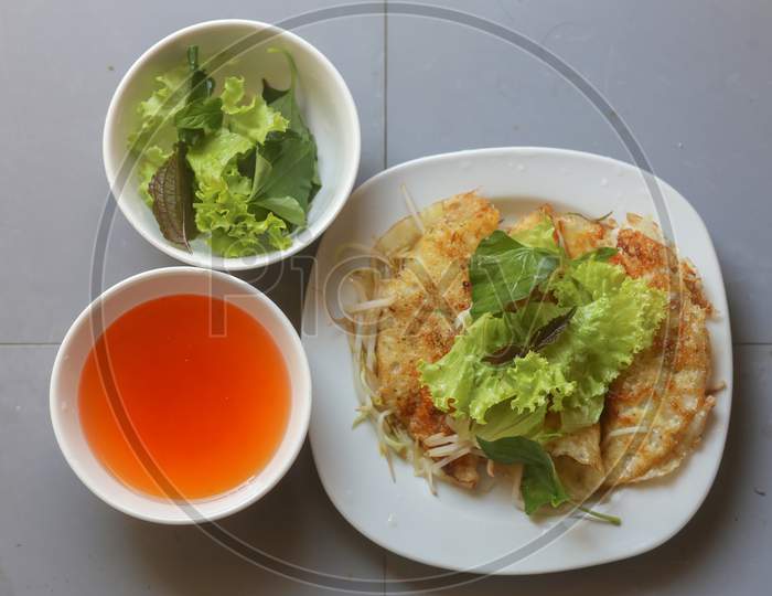 Close-Up Of Crispy Vietnamese Pancake With Fresh Vegetable And Fish Sauce