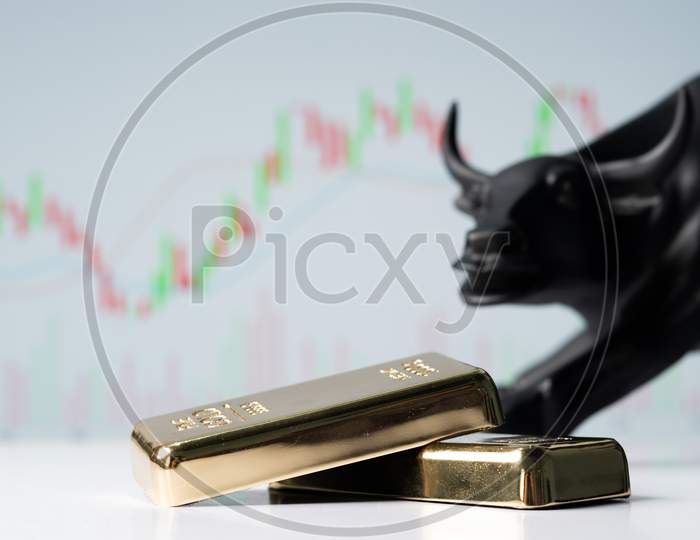 Focus On Gold Bars, Concept Of Bullish Or Boom In Gold Market Shares Or Stocks Showing By Bull Behind The Gold Bars With Charts In Background.