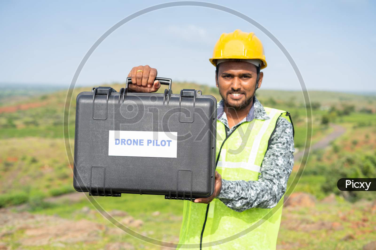 Focus On Case Drone, Pilot With Protective Work Wear And Hard Hat Showing Drone Case By Looking Camera - Concept Of Professional Uav Operator Or Aerial Filmmaker