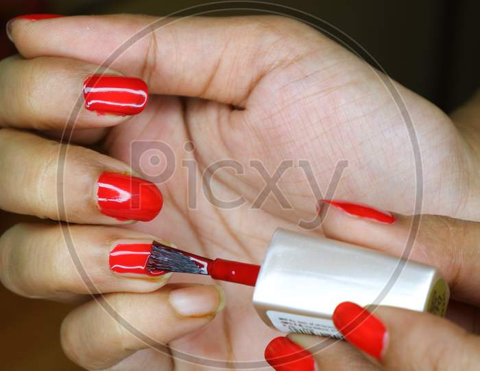 Woman Putting Red Colour Nail Polish On Her Nails.