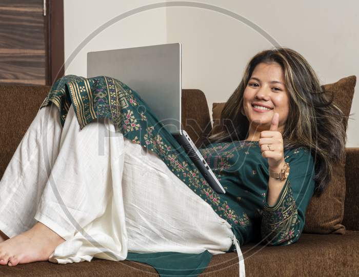 Young Indian Girl Showing Thumbs Up While Looking The Camera. Indian Ethnic Girl Working On Her Laptop, Working On Her Office Work. Independent Girl Working On Her Laptop.