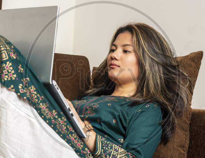 Thoughtful Indian Girl, Working On Her Laptop With Focus. Ethnic Freelancer Girl Working For Her Clients, Working On A Pc And Looking At The Screen With Focus.