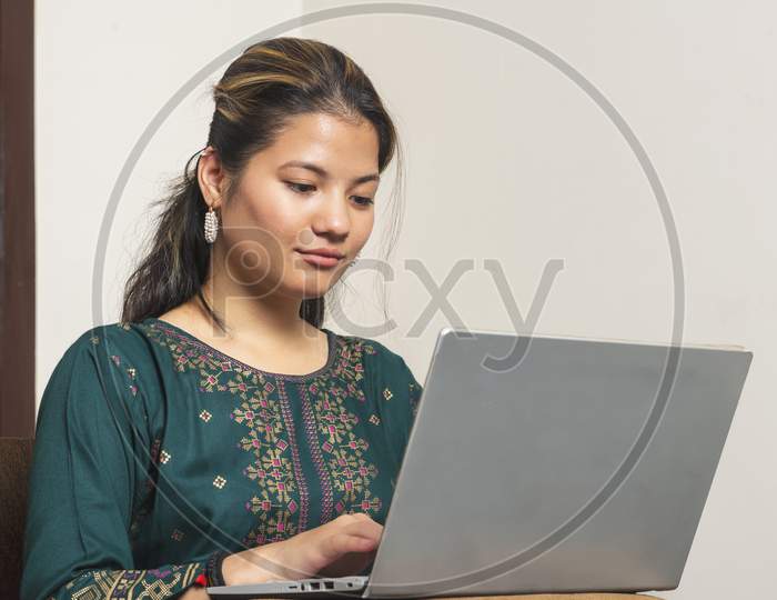 Young Indian Girl Smiling While Looking Into The Camera. Indian Girl Working On Her Laptop.