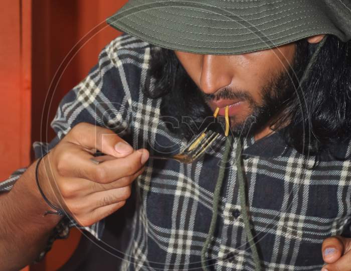 Closeup of a bearded and long haired man with wearing boonie hat during eating noodles in the cafe