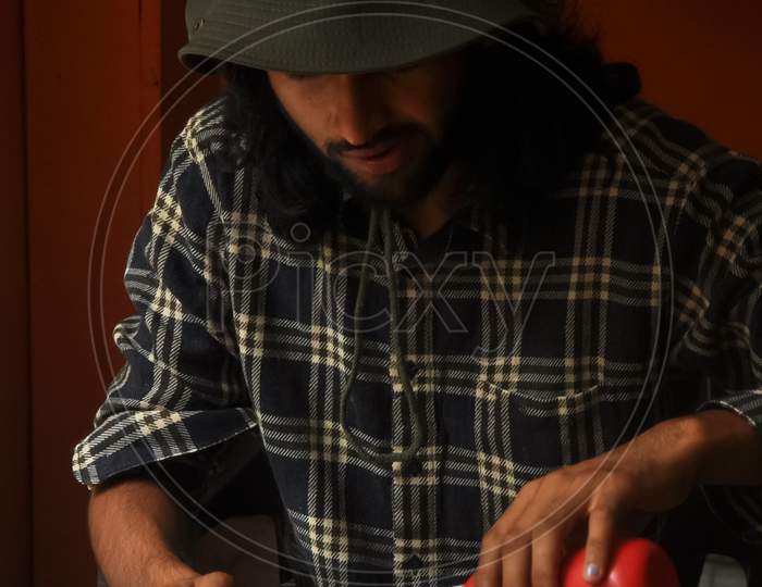 A bearded and long haired young man eating noodles in the restaurant during Covid-19 pandemic. A man with wearing boonie hat during eating fast food