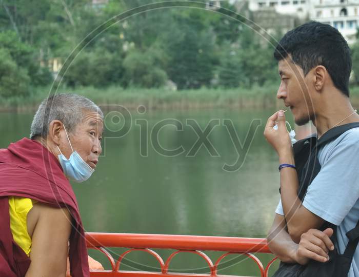 Mandi, Himachal Pradesh, India - 08 01 2021: A asian young guy having talk with lama (Buddhist Monk) in outdoor during coronavirus pandemic