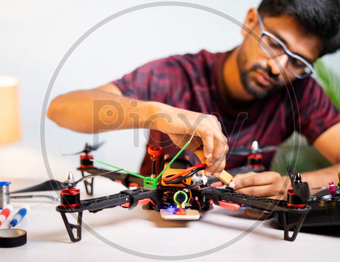 Selective Focus On Quadcopter, Engineer Student Connecting Battery To Drone At Home Laboratory - Concept Of UAV Experiment By Testing And Assembling