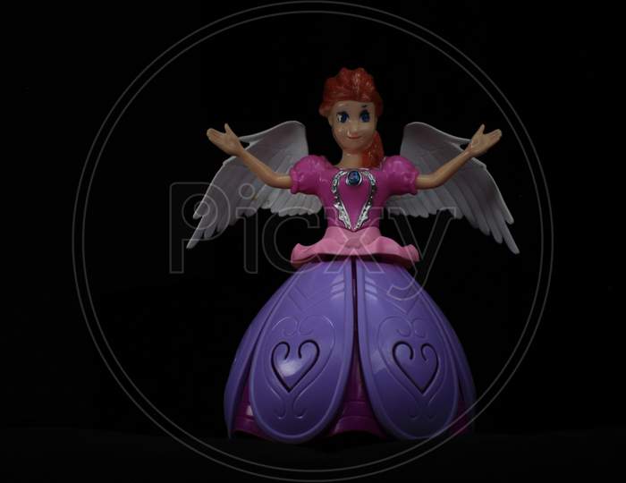 Colorful Light Painting In Front And Behind The Beautiful Angel Doll On The Black Background