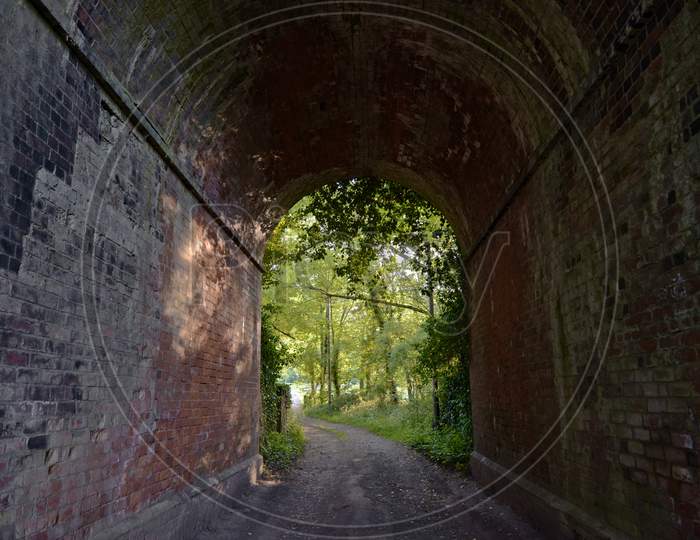 Red Brick Tunnel Contains A Muddy Double-Track Lane That Opens Out Into Deciduous Forest Greenery.