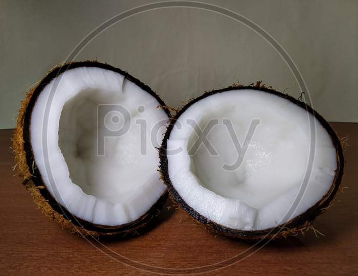 Two halves of coconut on wooden surface