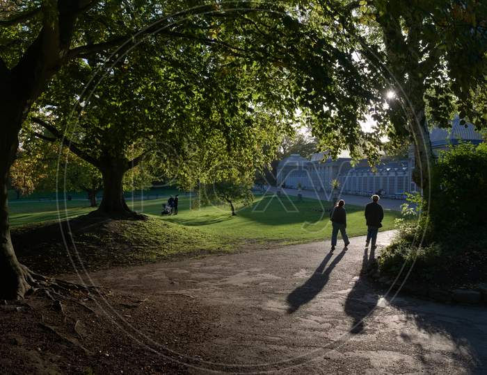 A Silhouetted Couple Walk Towards Iconic Greenhouses Of Sheffield
