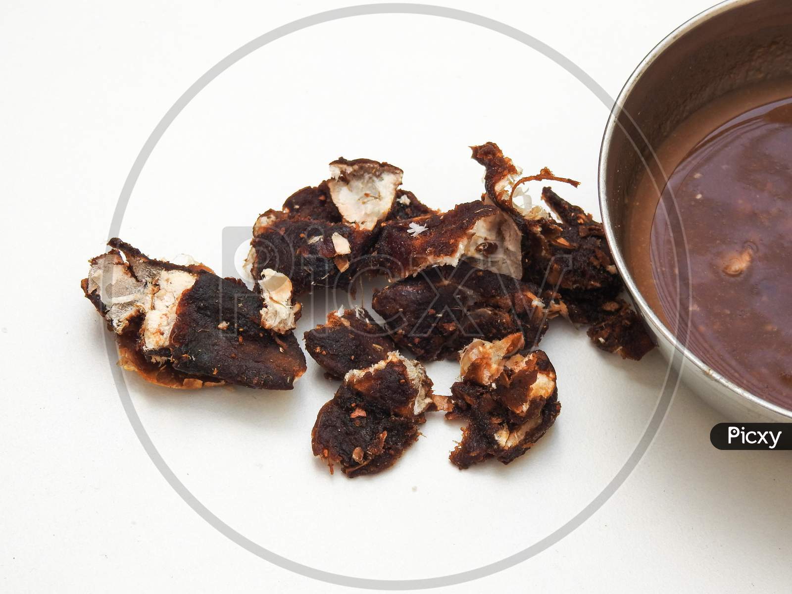 Heap Of A Indian Tamarind Fruit And Juice In A Steel Bowl Isolated On White Background