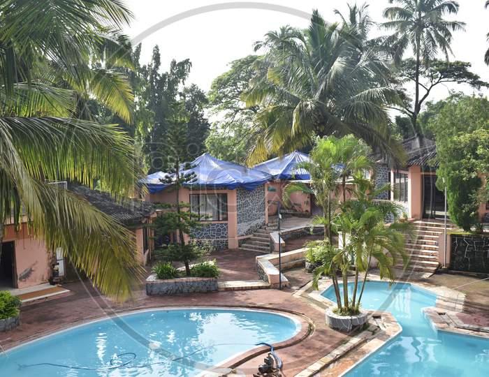 Resort Photos With Two Swimming Pools And Rooms Surrounded With Coconut Trees.