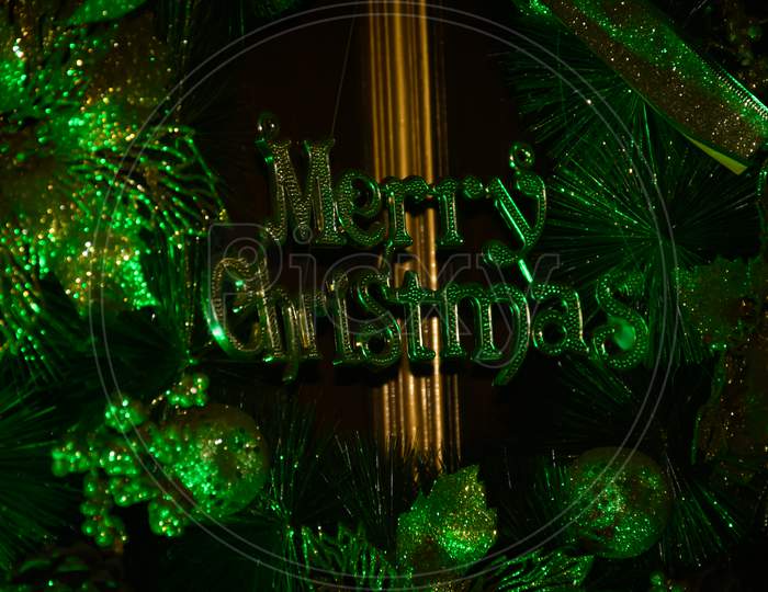 A Decorative Christmas Wreath With Merry Christmas Text On Brown Wooden Door