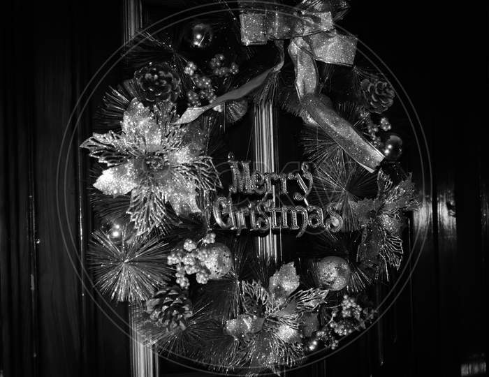 White And Black Photo Of A Decorative Christmas Wreath With Merry Christmas Text On Brown Wooden Door