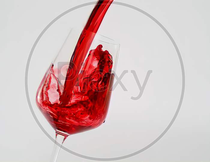 Red wine is pouring into a glass goblet on a white background. alcoholic drinks.
