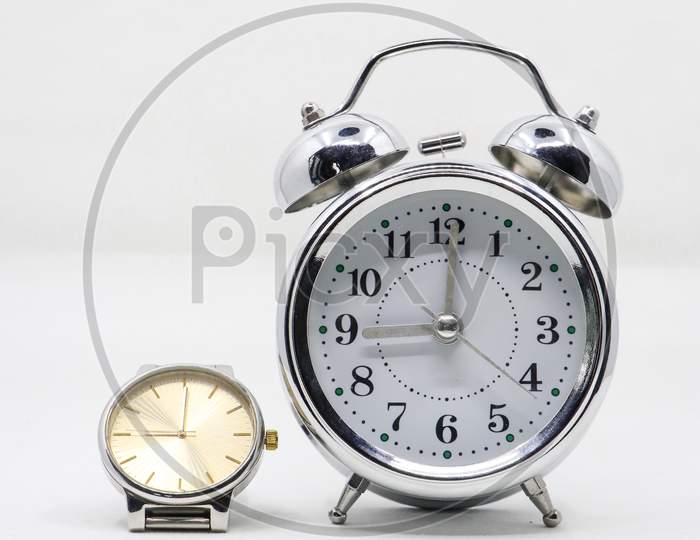 a silver luxury watch and a metallic silver alarm clock