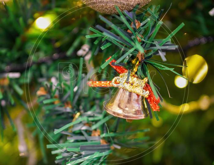 A Bell With Christmas Word As Decoration At Fake Tree