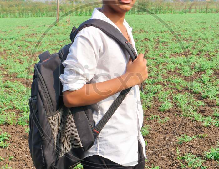 Indian Child College Bag And Standing At Agriculture Field.