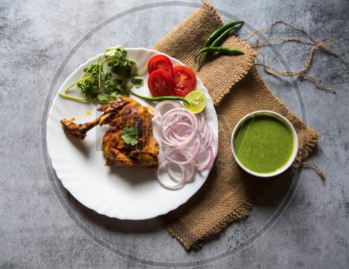 Top view of Coriander leaf on chicken tandoori in a plate along with condiments