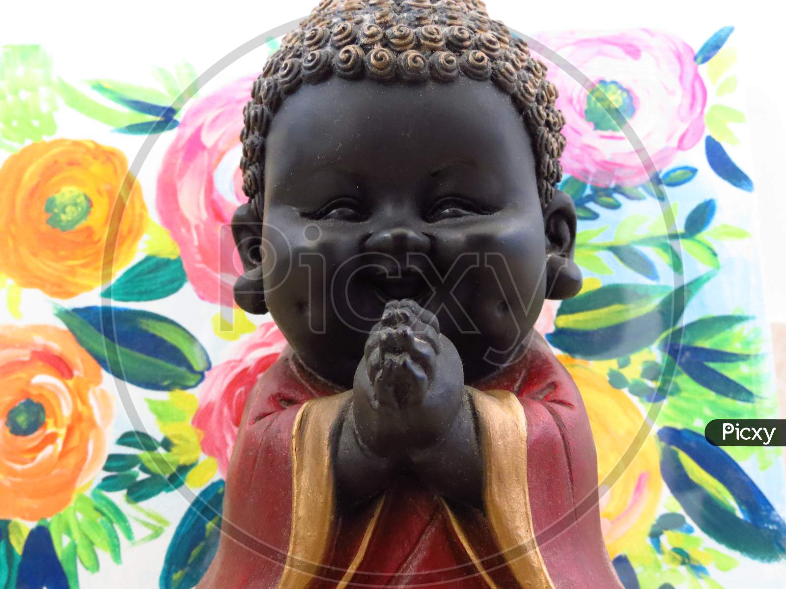 Praying happy Buddha statue with floral background.