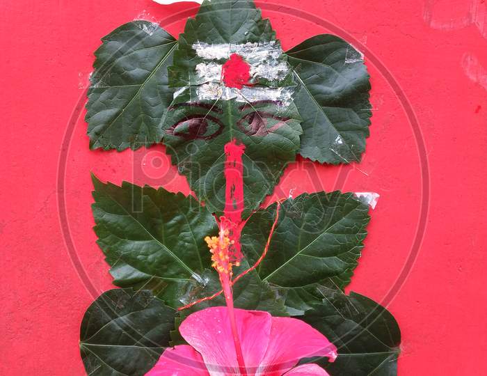Lord ganesha made by green hibiscus leaves with red background