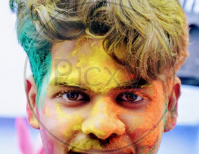 A middle aged indian boy with colours on face in Holi festival