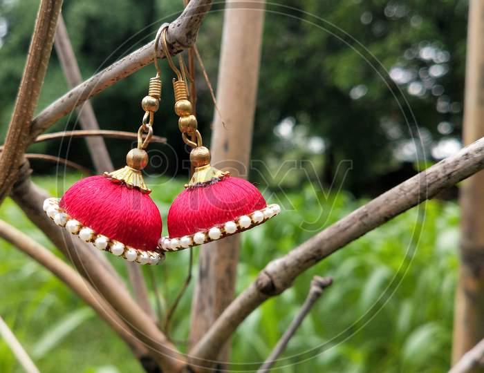 A beautiful jhumka  made by red thread with blur background